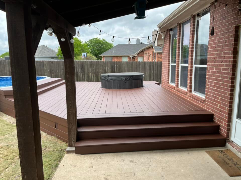 Covered backyard deck with brown steps, brick house wall, and a circular hot tub in the center