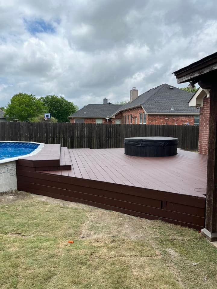 Backyard deck with a round hot tub, fenced yard, and cloudy sky