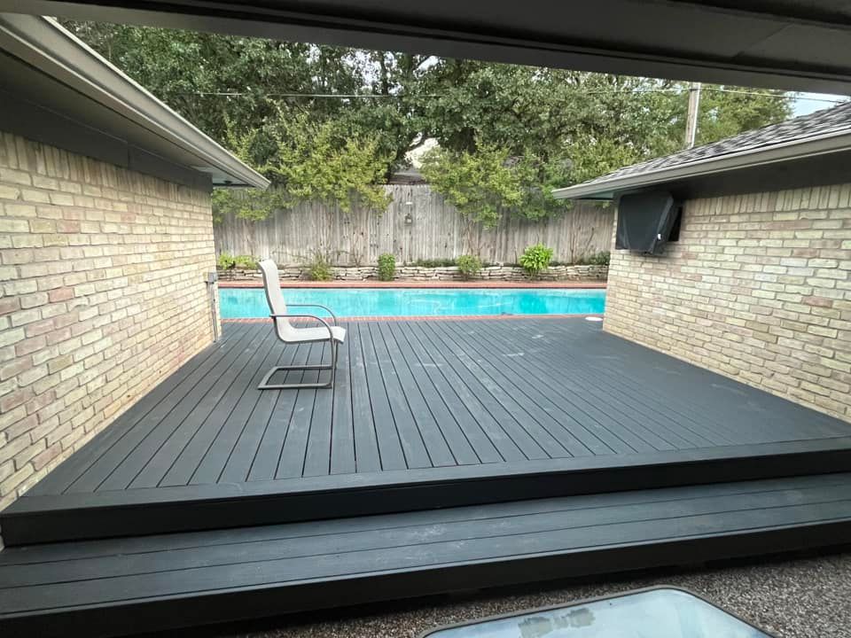 Backyard deck with a white chair beside a turquoise swimming pool and brick house wall