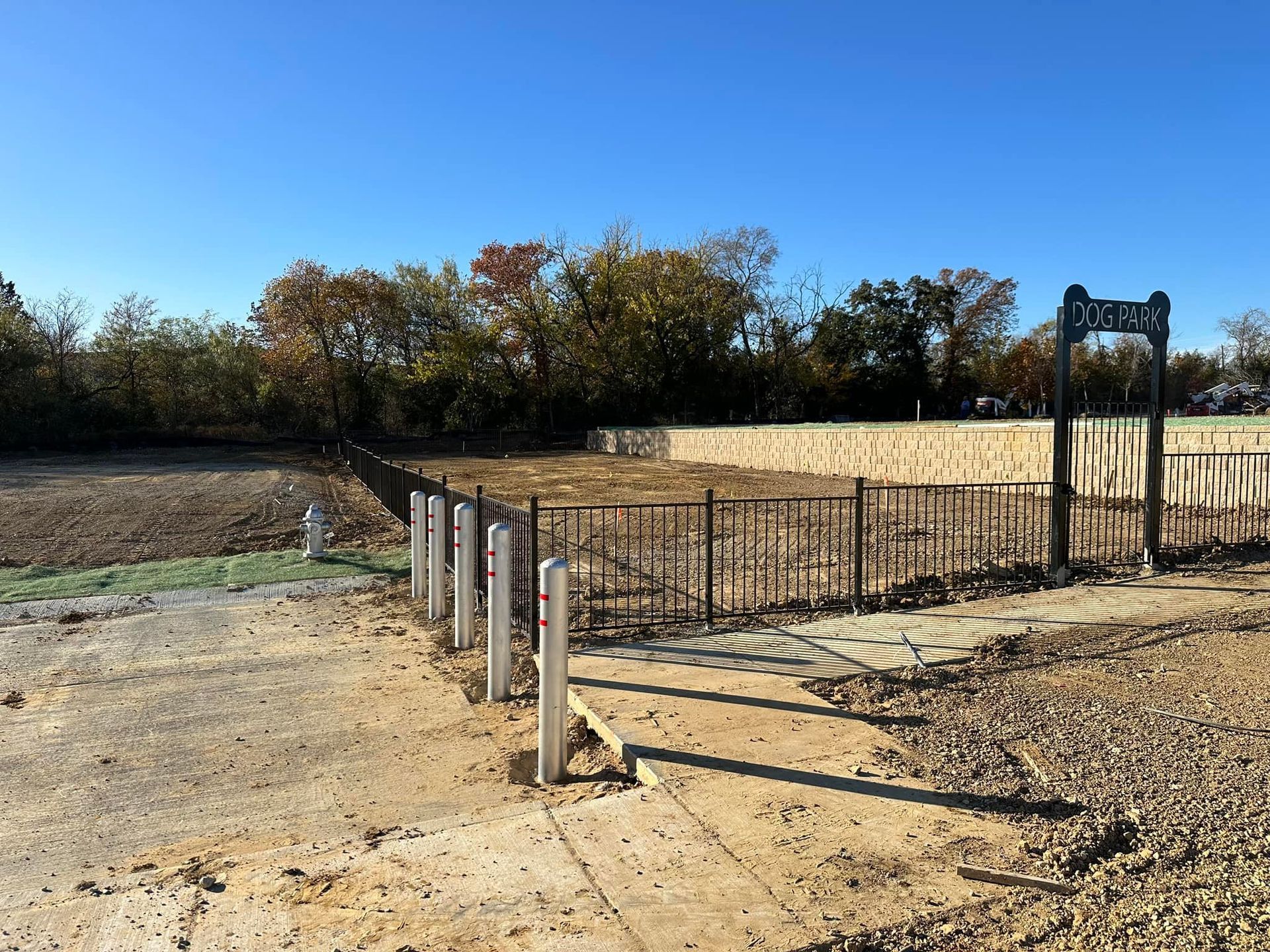 Abandoned fenced concrete pad beside grassy field under clear blue sky