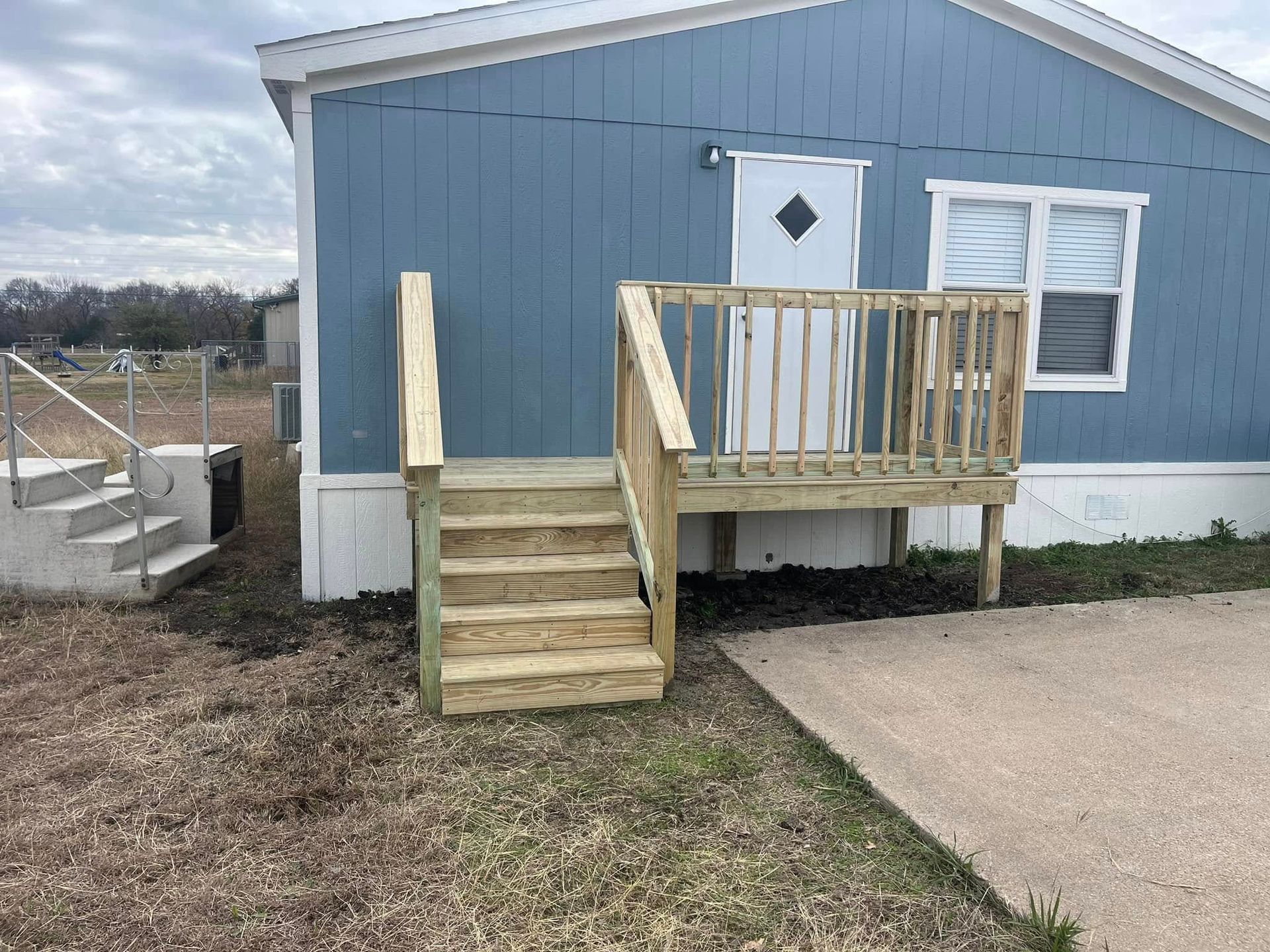 Blue house exterior with front steps and a small wooden ramp beside the door