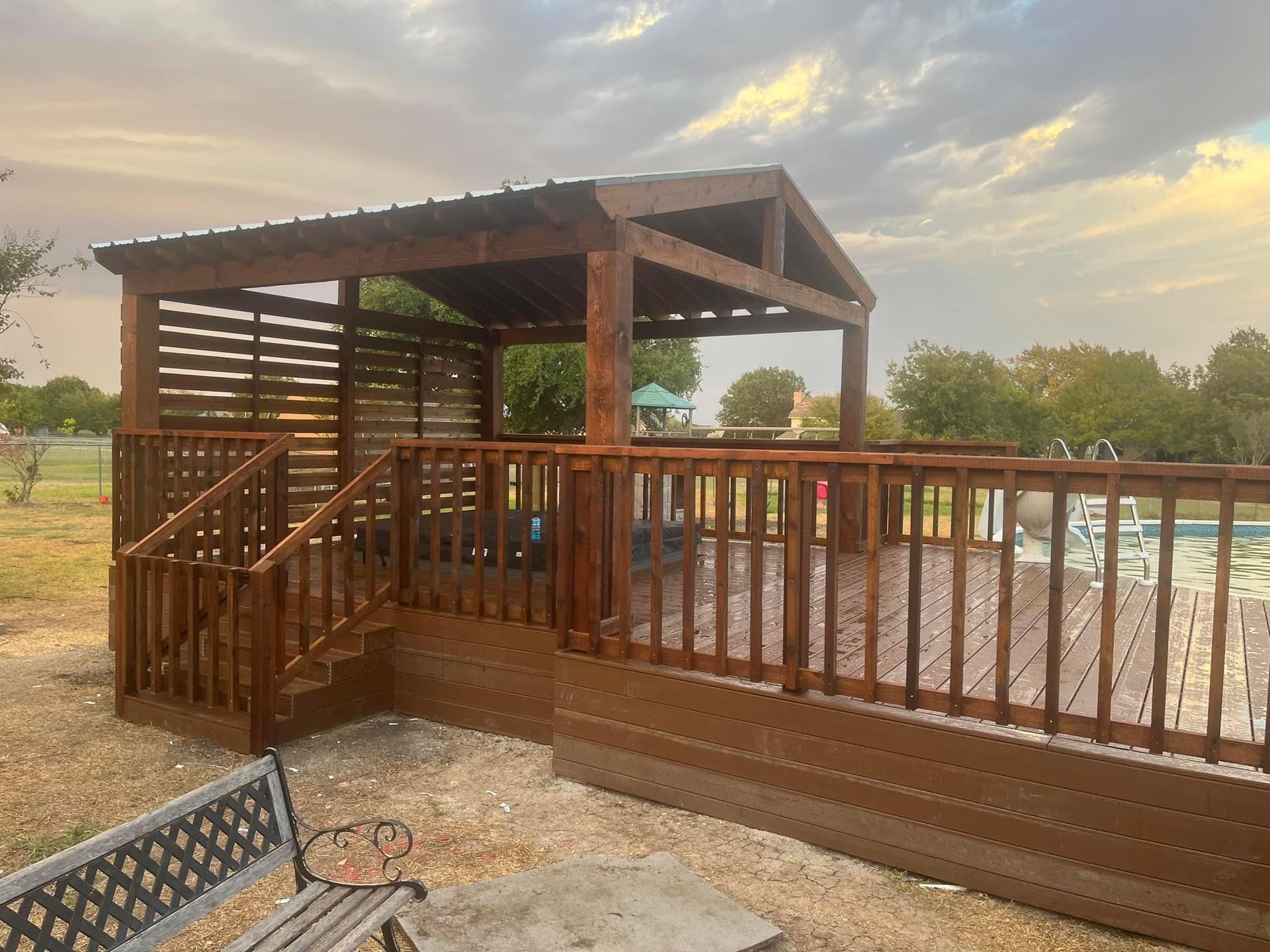 Wooden deck and pergola overlooking a flooded yard at sunset
