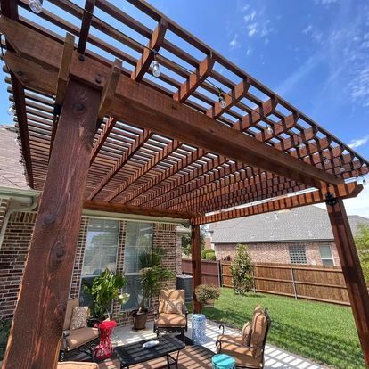 Backyard patio with wooden pergola, outdoor seating, potted plants, and a green lawn in sunlight