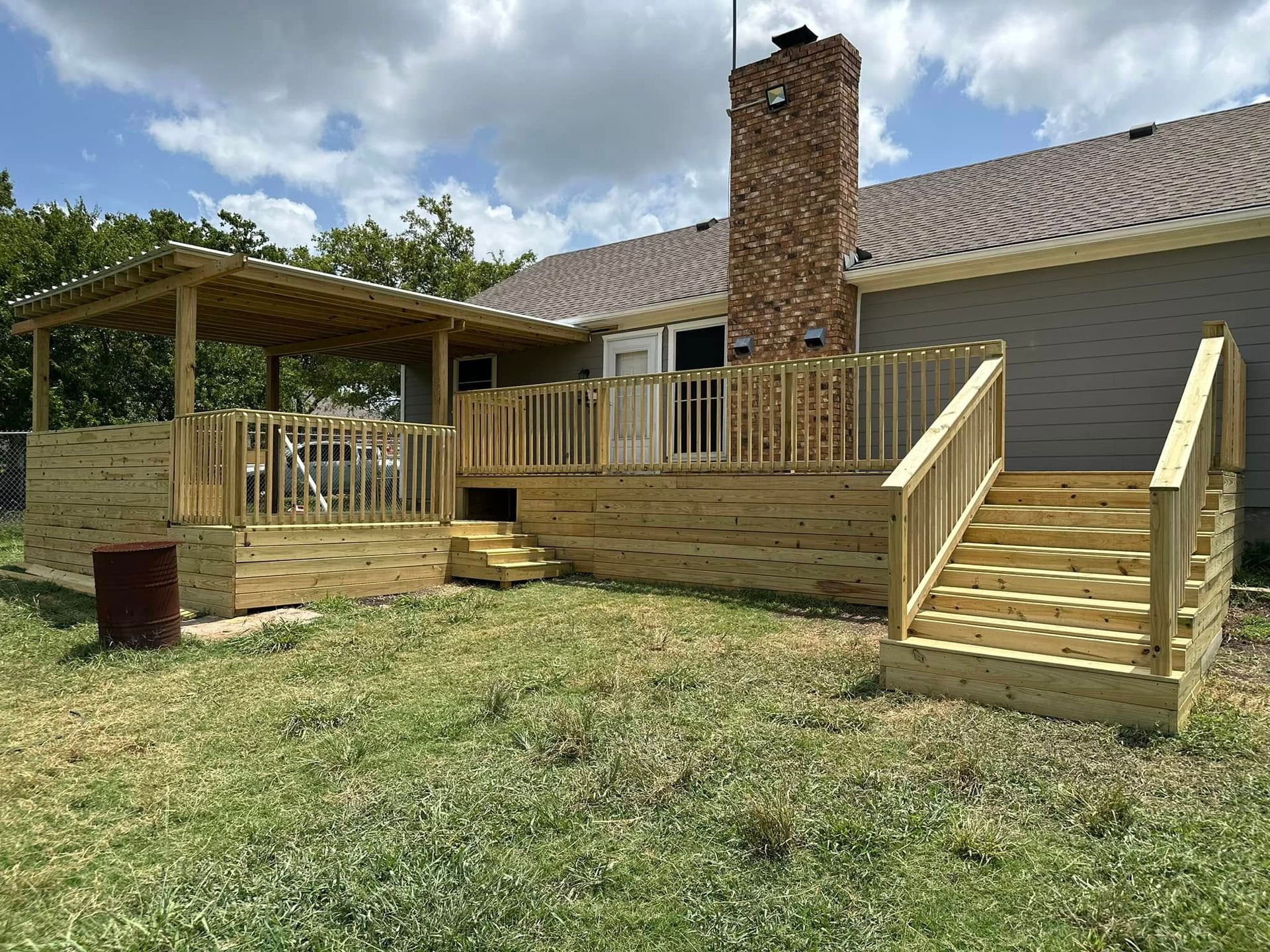 Wooden wheelchair ramp and steps leading to a brick house deck with a pergola, under a cloudy sky