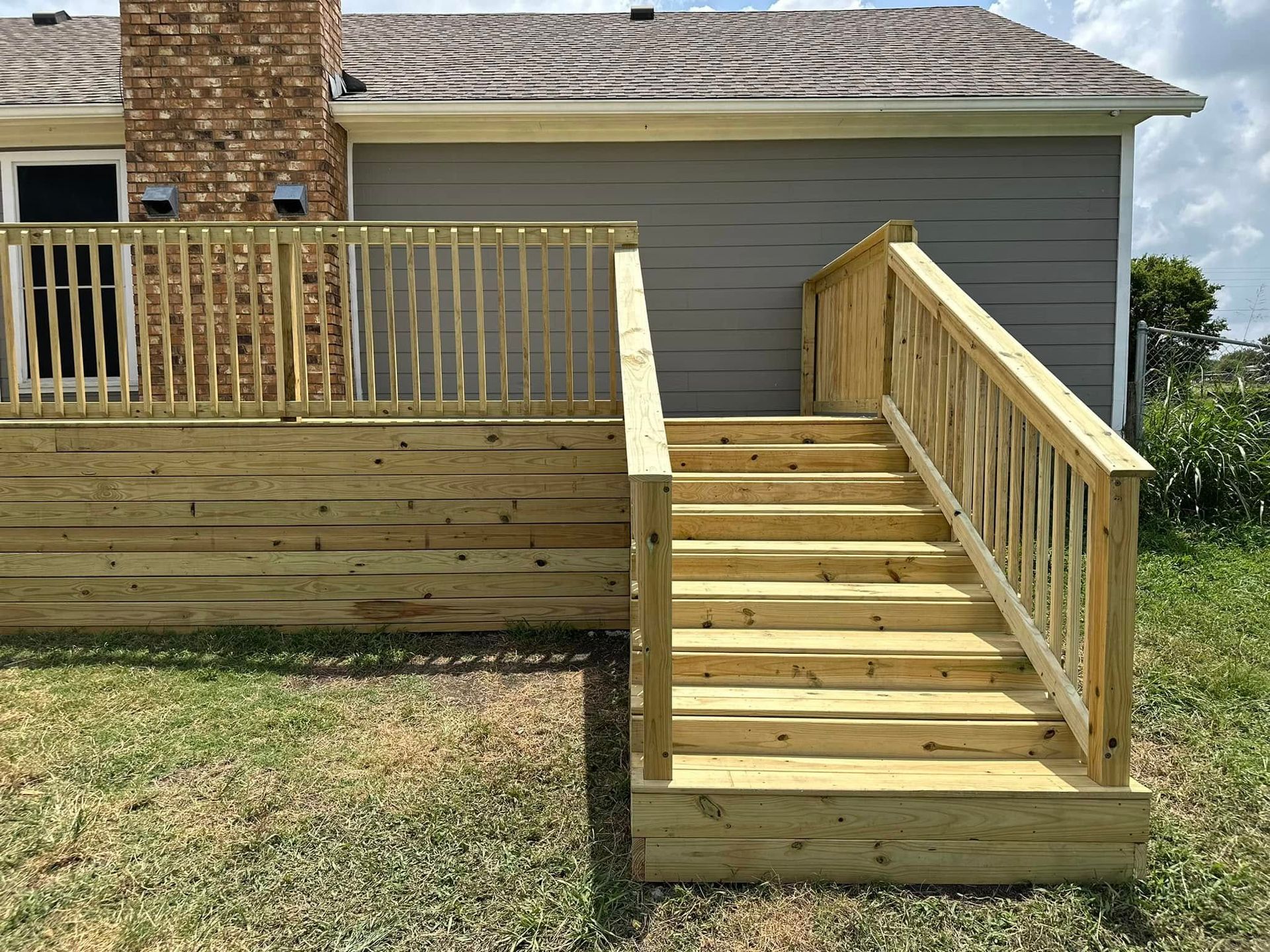 Wooden accessibility ramp and stairs leading to a raised deck beside a house