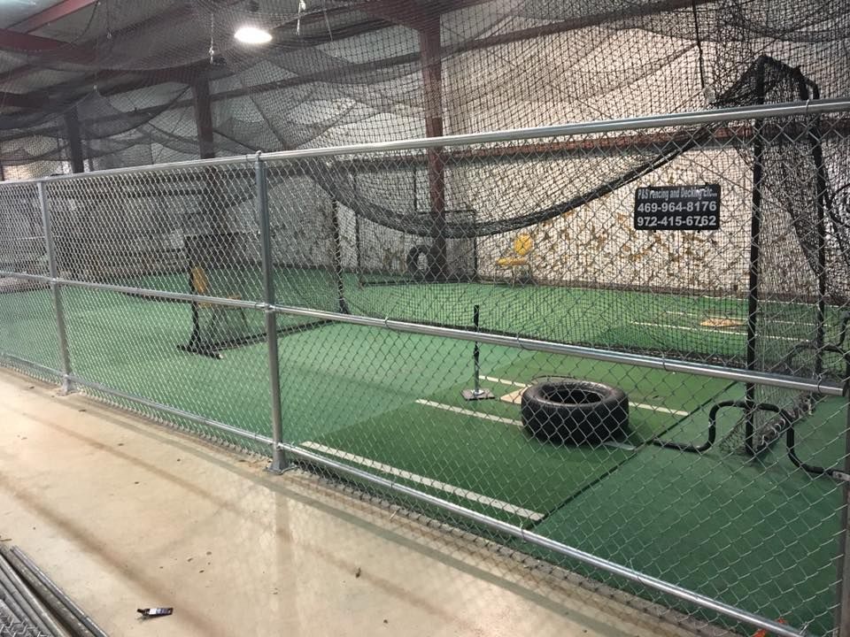 Indoor batting cage with green turf, netting, and a tire drill obstacle