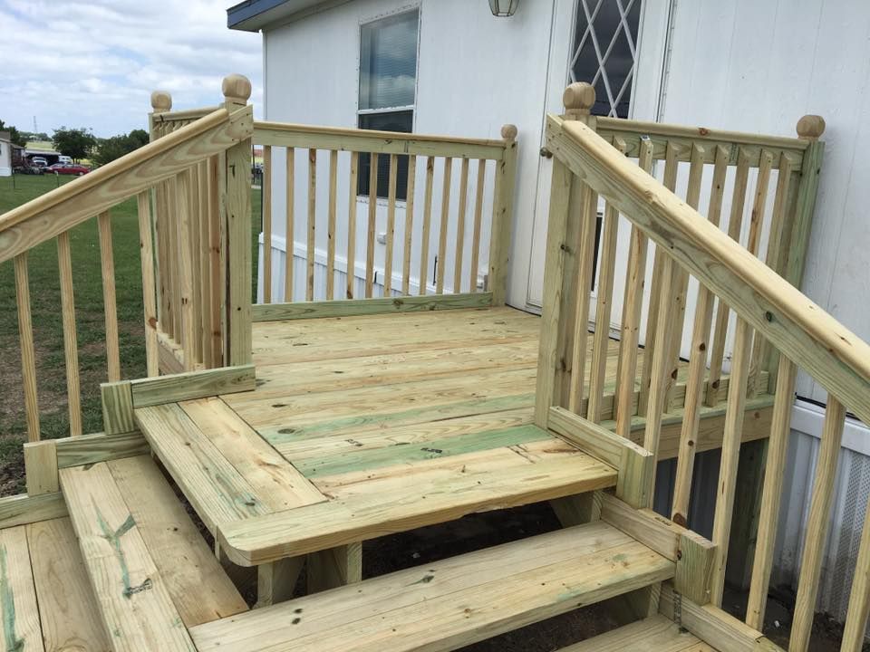 Wooden ramp and steps leading to a house deck, with railings and a small landing.