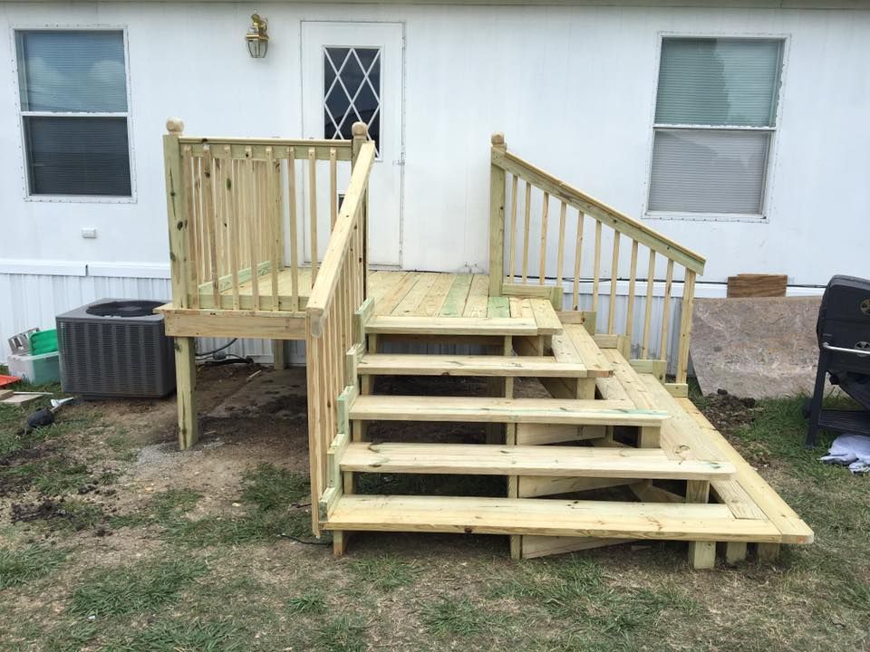 Wooden wheelchair ramp and steps leading to a house porch from a patchy yard