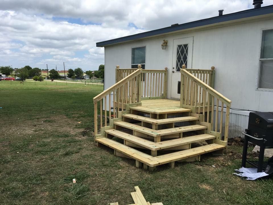 Wooden wheelchair ramp and steps leading to a house entrance beside a grassy yard
