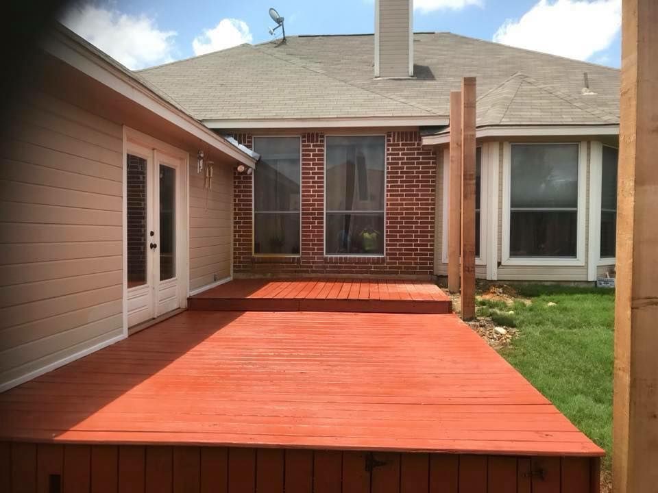 Backyard deck with fresh red wood flooring, brick step, and patio doors between two houses