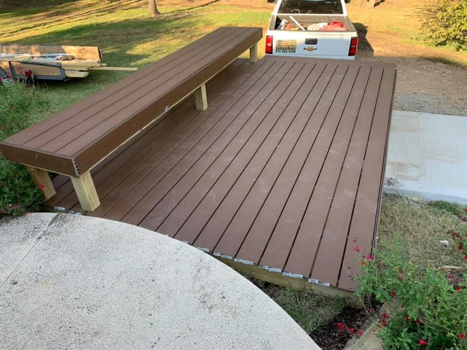 Brown wooden deck and bench in a backyard, with a white car parked behind it.