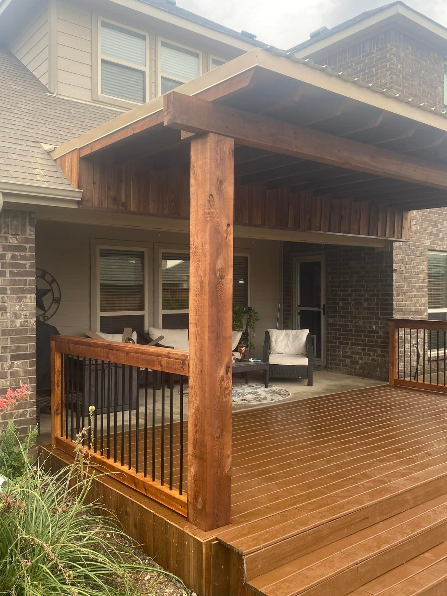 Covered wooden deck with railing and steps attached to a brick house exterior