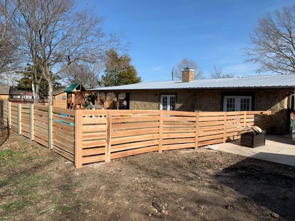 Wooden deck and privacy fence around a house in a sunny yard