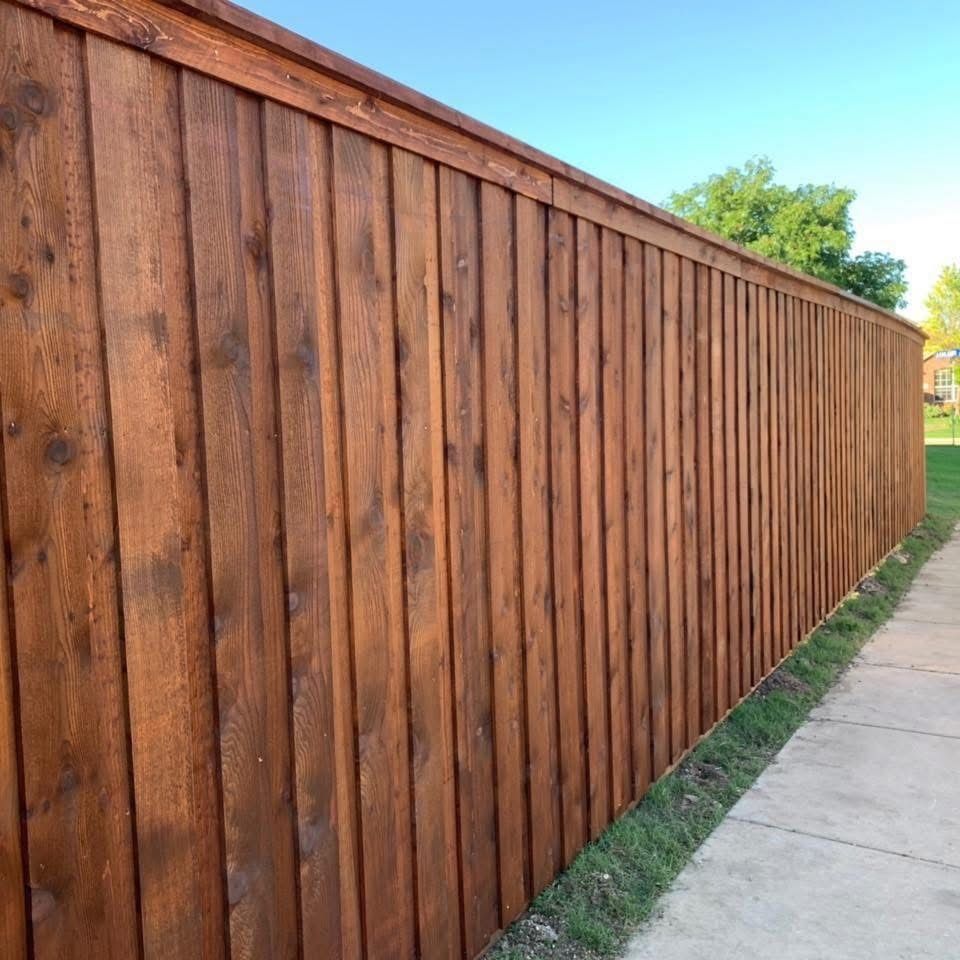 Long wooden fence beside a concrete sidewalk on a sunny day
