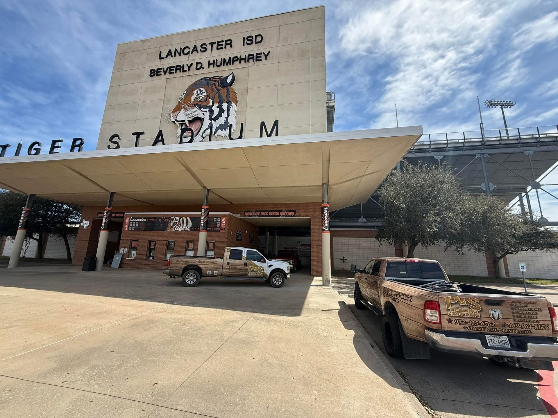 Langston Stadium entrance with brick facade, white canopy, and parked pickup truck under a partly cloudy sky