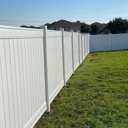 White vinyl fence along a grassy yard under bright sunlight