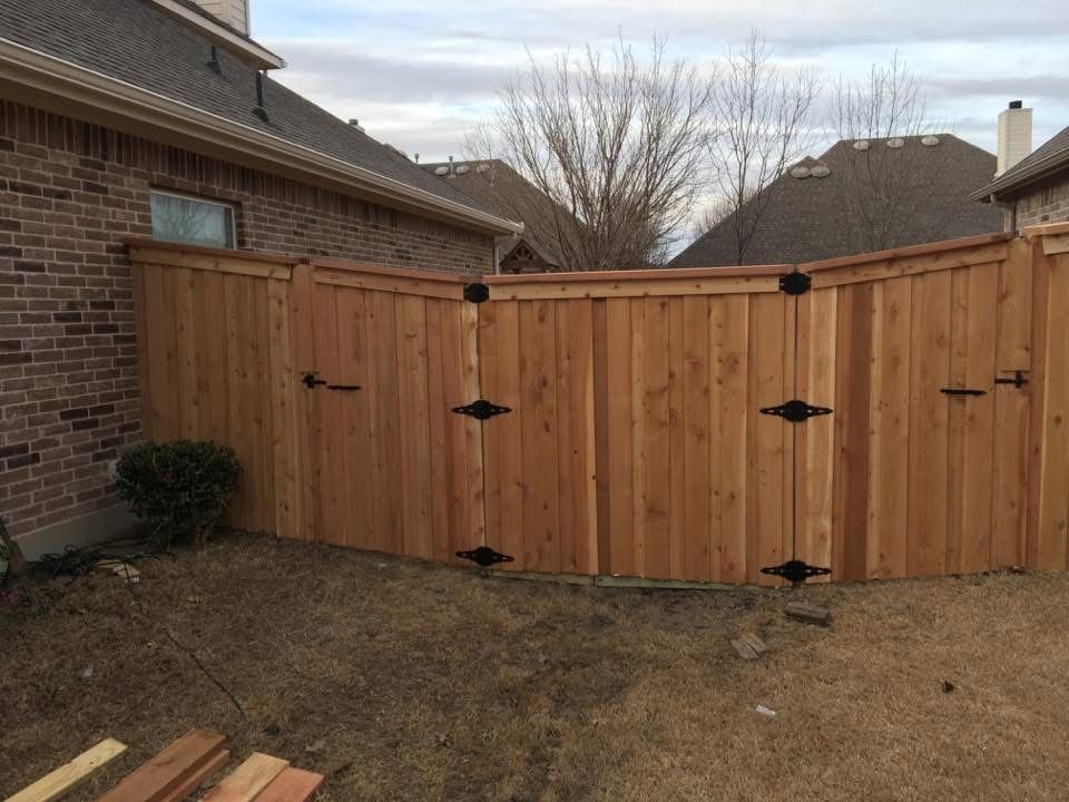 Backyard wooden privacy fence and gate beside a brick house