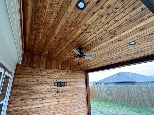 Wood-paneled covered patio ceiling with recessed lights, fan, and a view of mountains and backyard fence