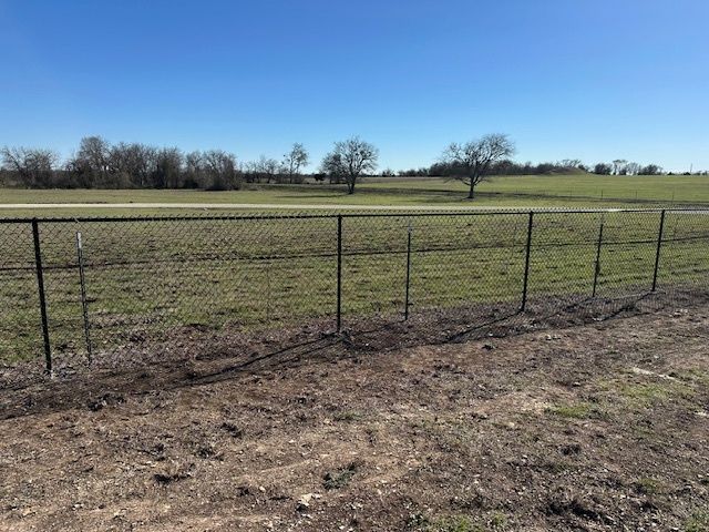 Wire fence along a grassy field under a clear blue sky
