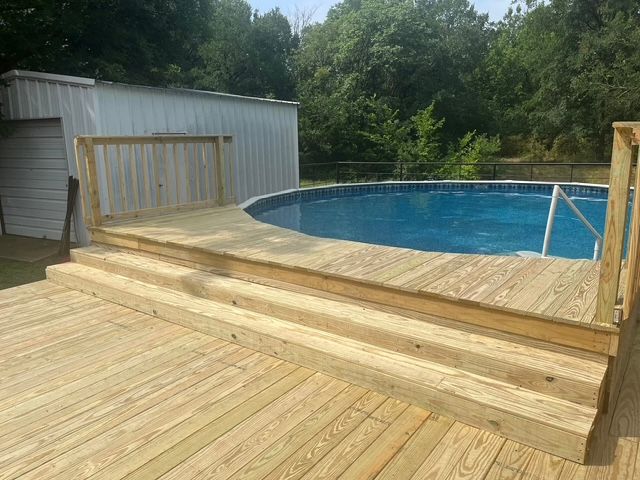 Wooden deck with steps beside an above-ground backyard pool and shed.