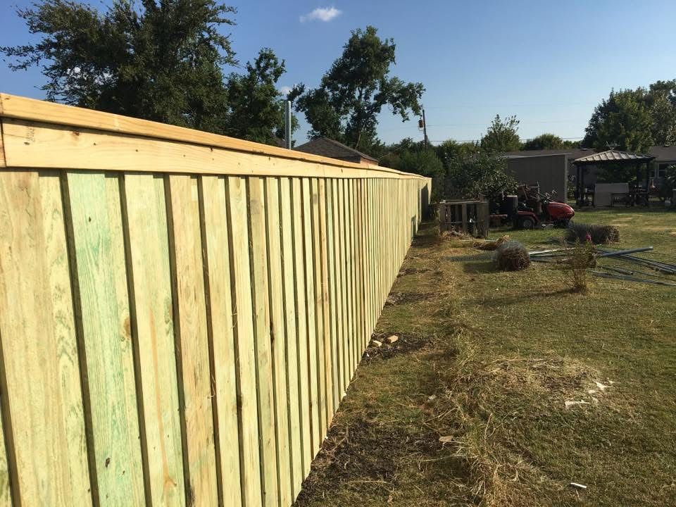 Long wooden fence along a grassy yard on a sunny day