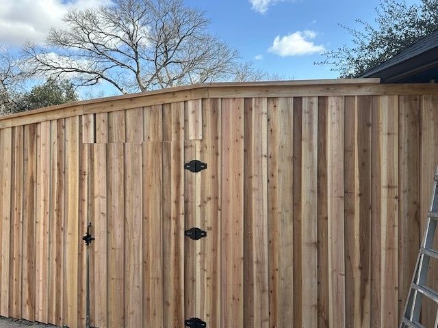 Tall wooden fence under a blue sky, with a ladder leaning at the right edge.