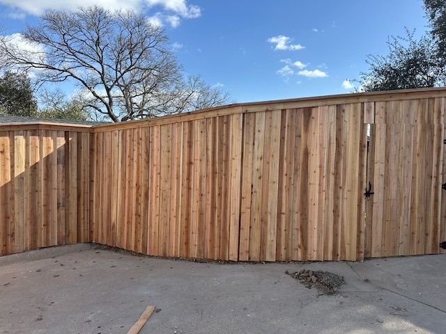 Wooden privacy fence around a concrete yard under a blue sky