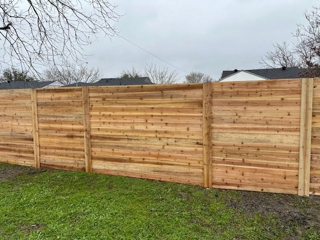 Wooden privacy fence along a grassy yard under a cloudy sky