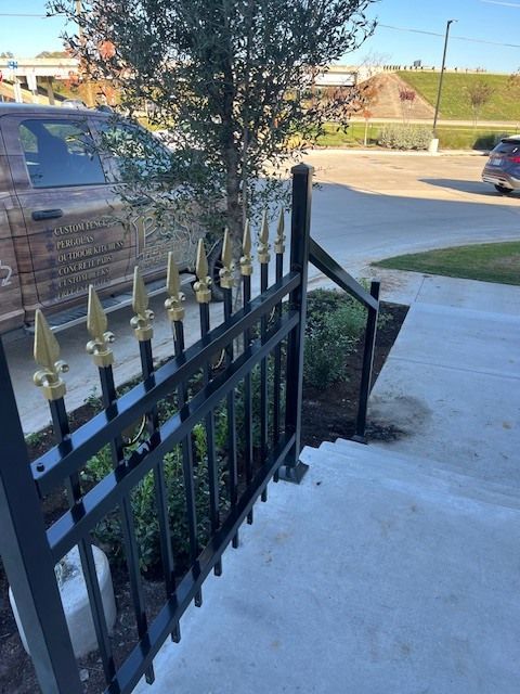 Front porch with black metal railing and gold finials, overlooking a driveway with a parked SUV and street beyond