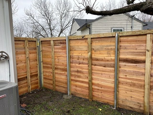 Wooden privacy fence in a backyard corner with bare trees and a house in the background