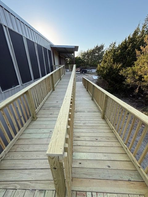 Wooden wheelchair ramp beside a building, with railings and trees in the background