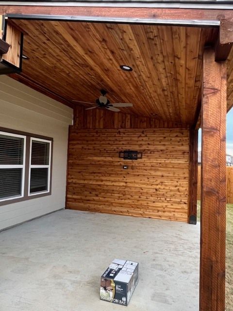 Covered patio with wood ceiling, ceiling fan, and a box on the concrete floor.