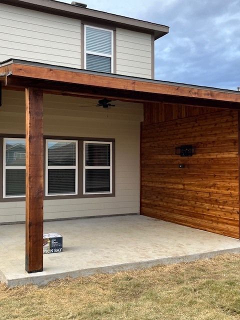 Covered patio with wooden posts and ceiling attached to a beige house