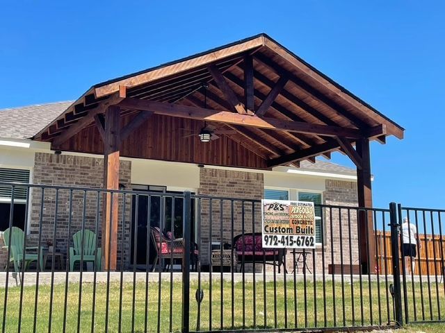 Community center with covered entrance, stone facade, black fence, and a sign by the door.