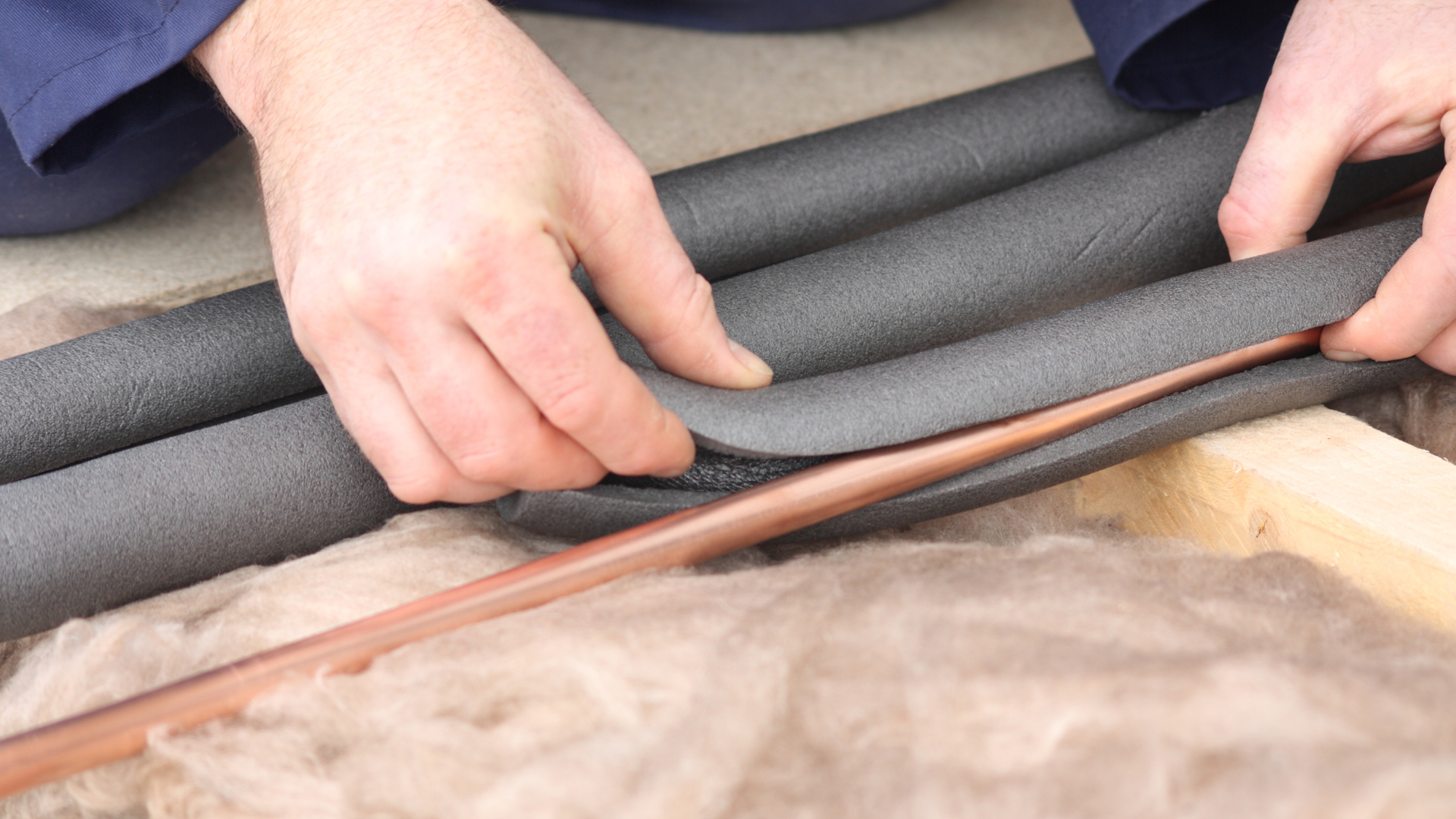 A person is holding a piece of foam and a copper pipe.