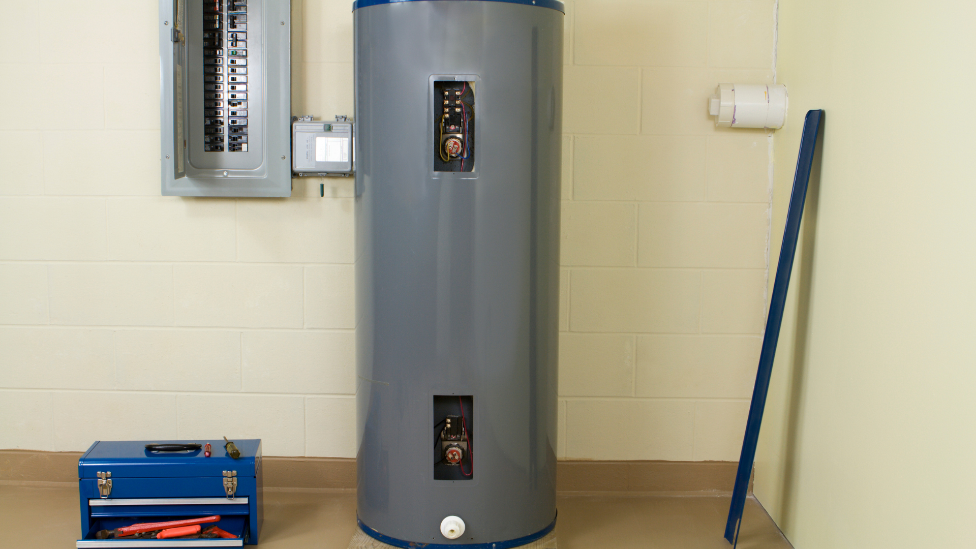 A water heater is sitting in a room next to a toolbox.
