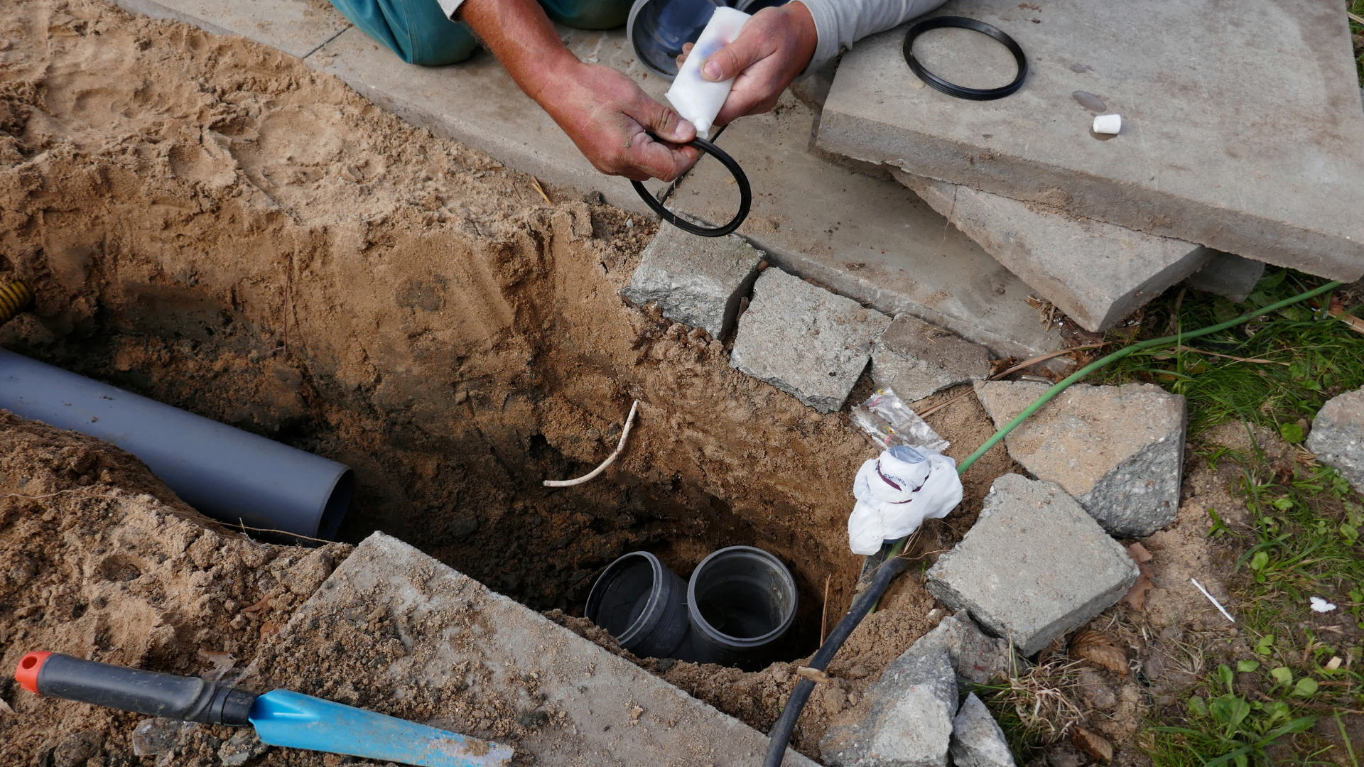 A man is working on a pipe in the ground.