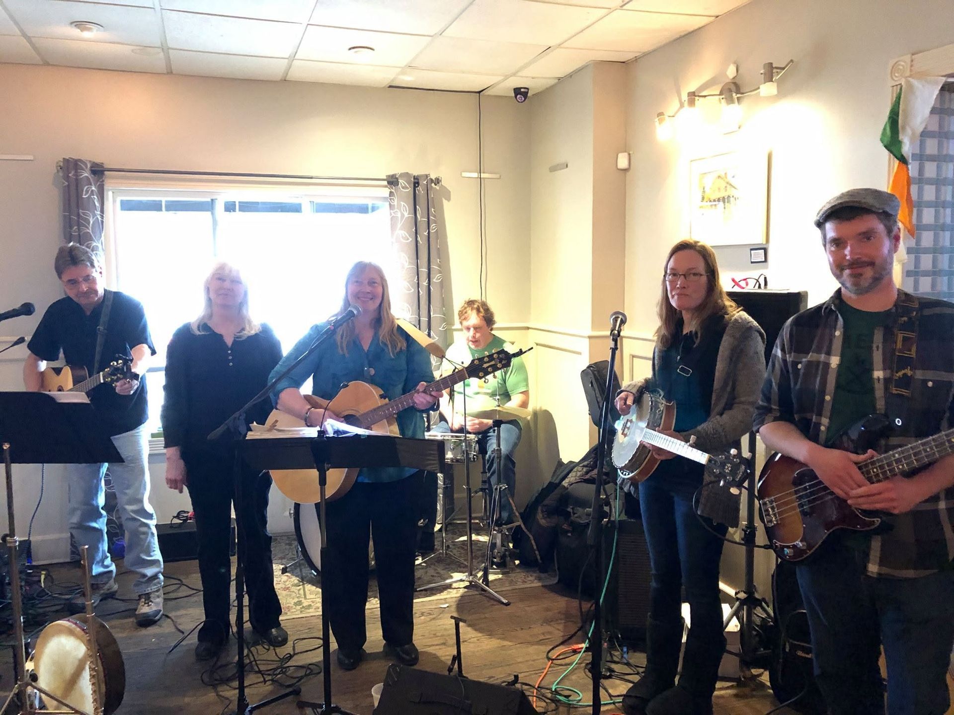 Live band performing indoors, with guitars, drums, and microphones in a small room