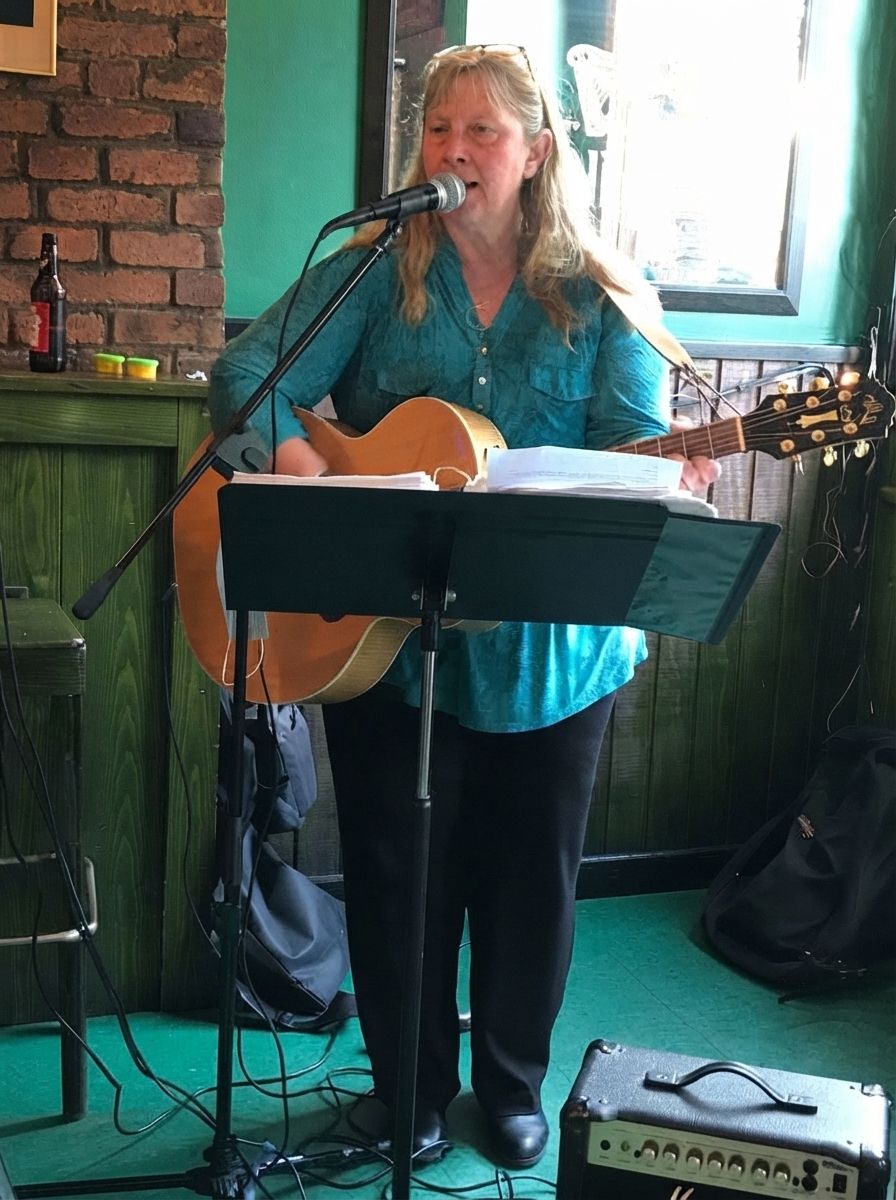 Singer performing with acoustic guitar and microphone on a small indoor stage Singer performing with acoustic guitar and microphone on a small indoor stage