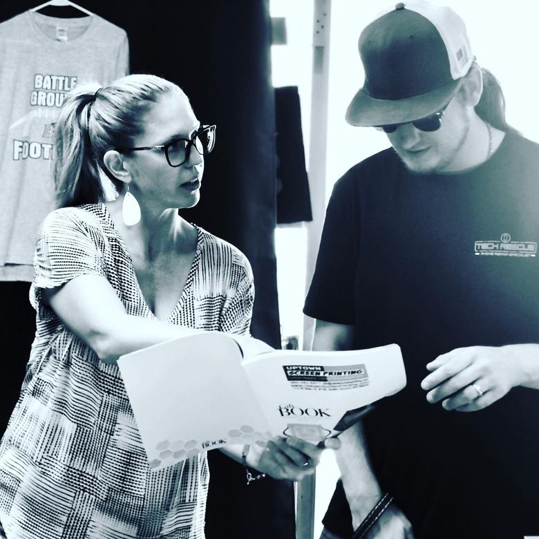 A black and white photo of a man and a woman looking at a book