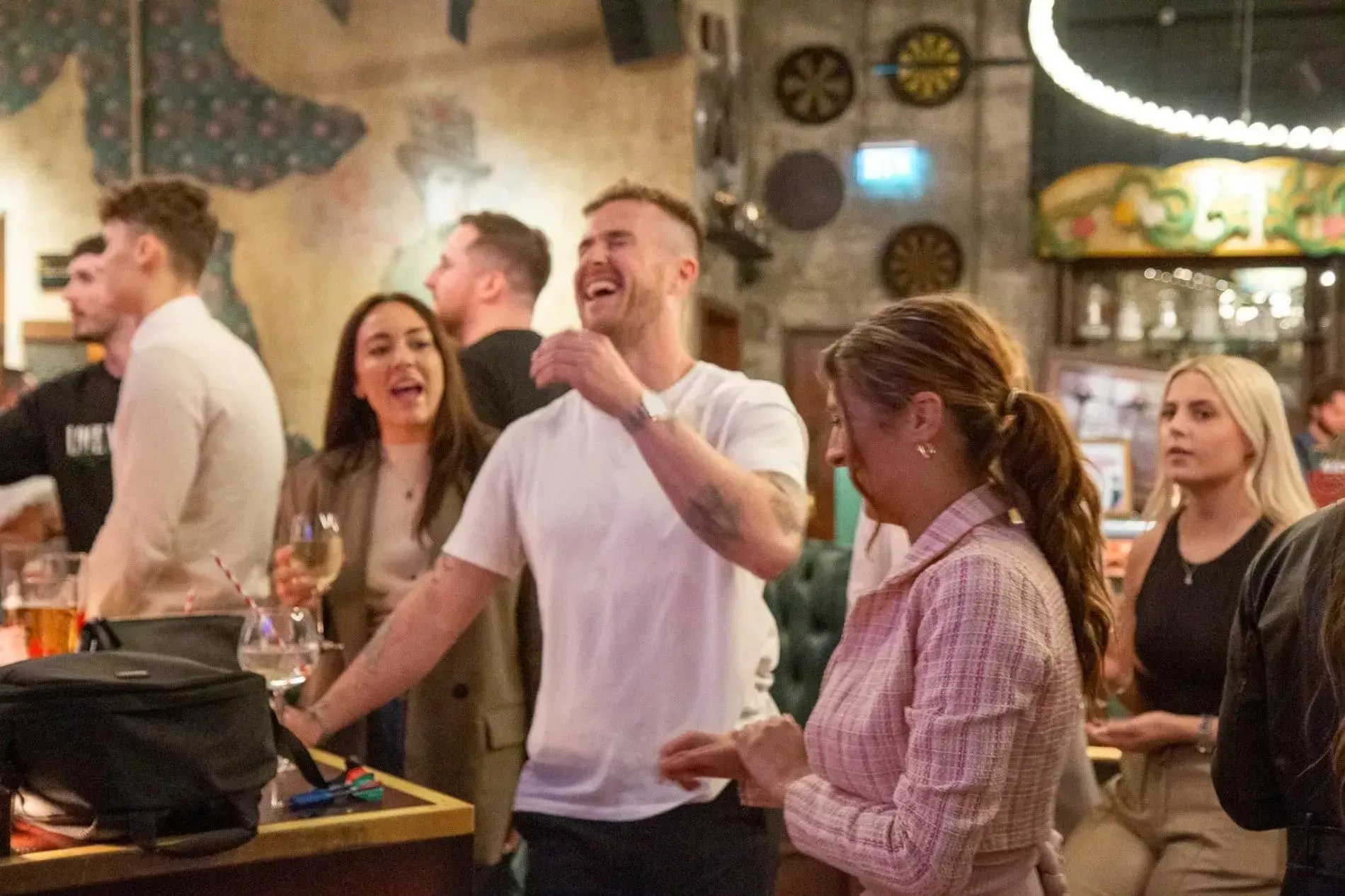 Group of people laughing and socializing in a bar.