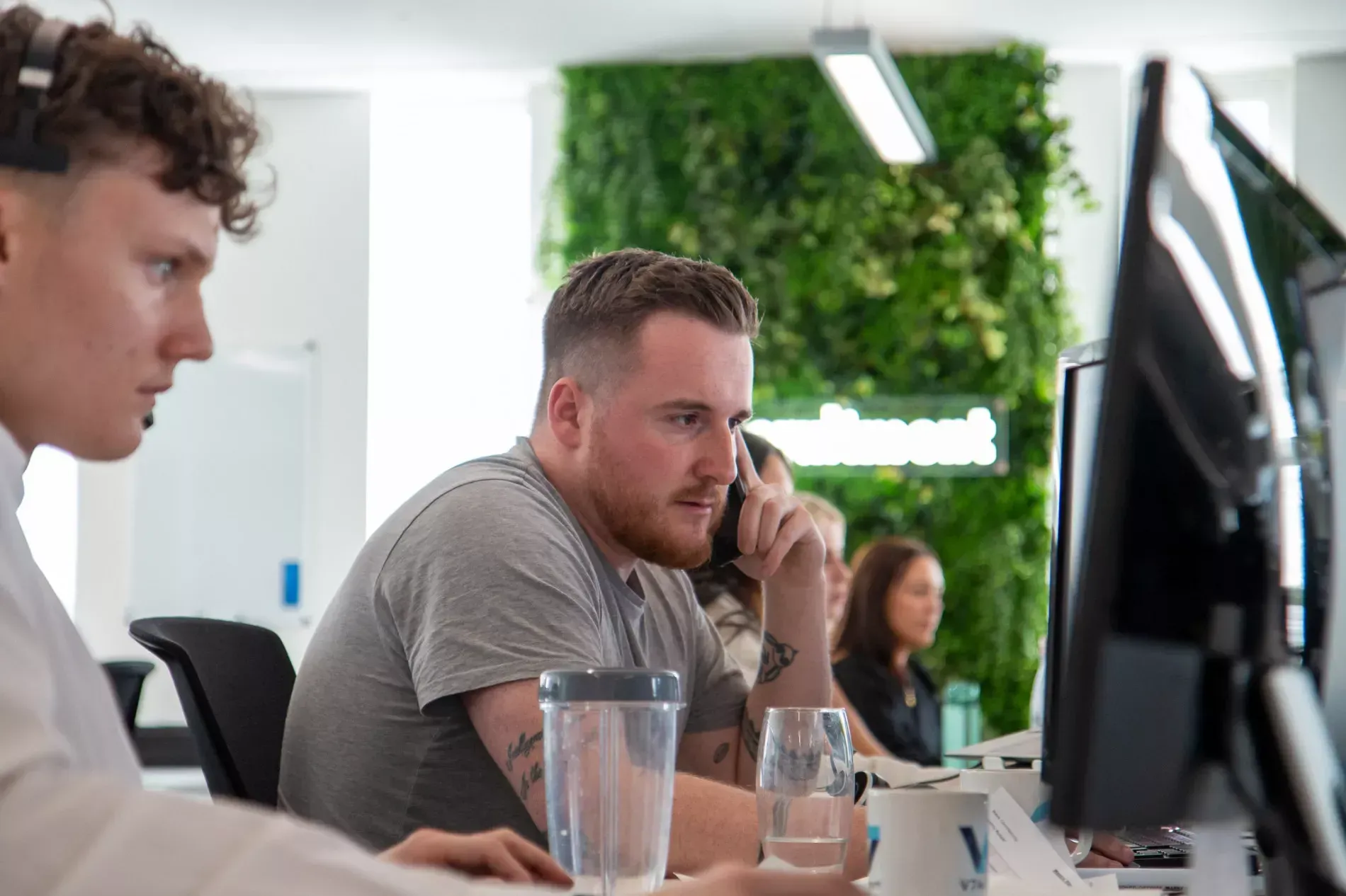 2 recruiters on the phone at their desks in the office