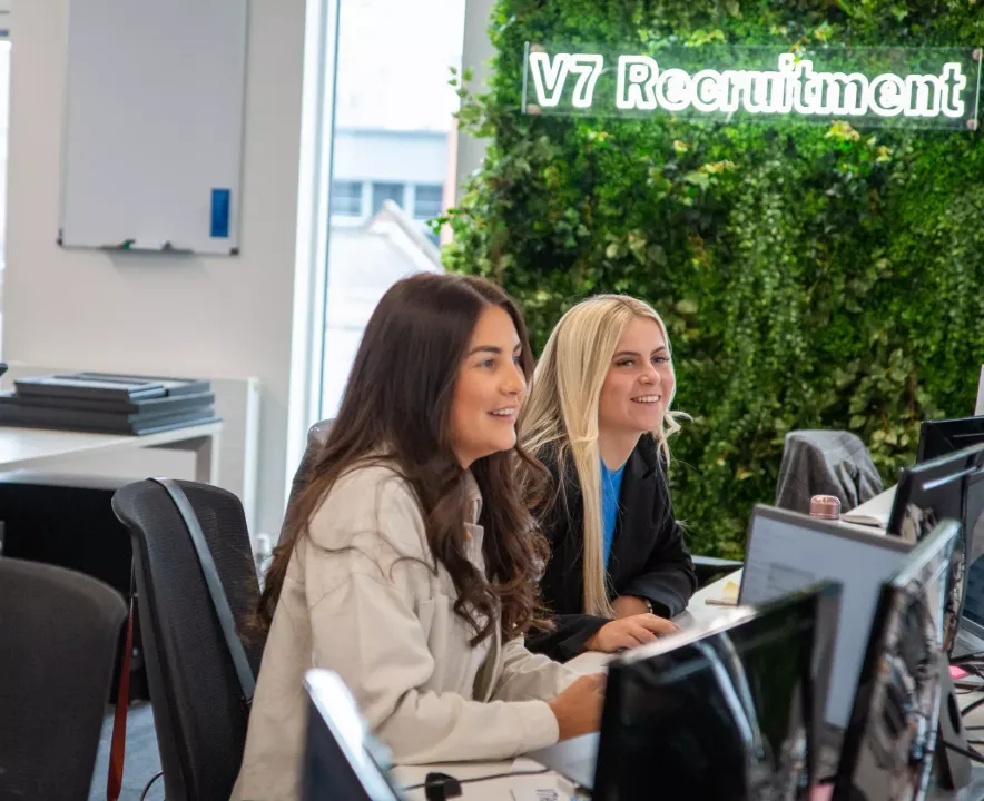 two female workers at their desks in an office