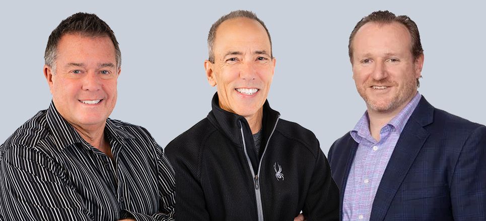 Three smiling men posing side by side against a light gray background