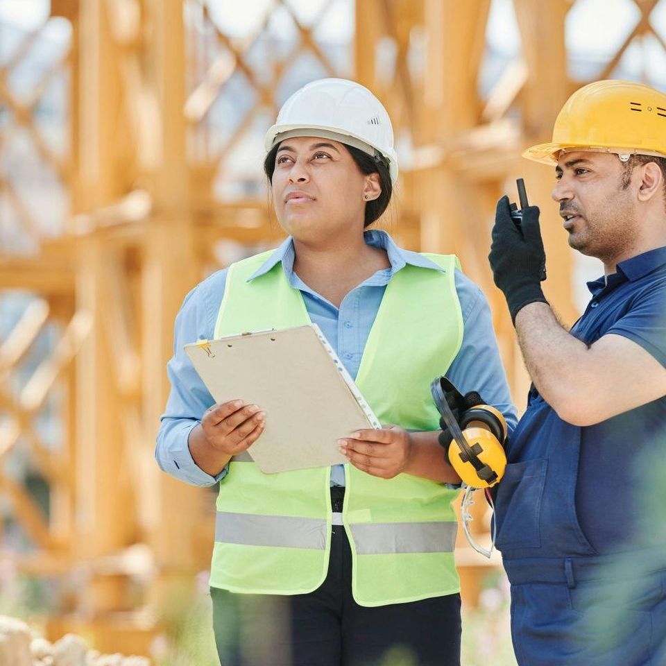 A man and a woman are standing next to each other on a construction site.
