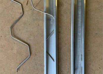 Metal wire spring and two aluminum rails on a tan surface