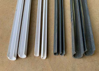Assorted white, gray, and black plastic trim or weatherstripping strips laid side by side on a surface