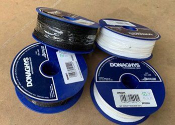 Four spools of Donaghy’s cord or twine in blue, white, and black on a cardboard surface