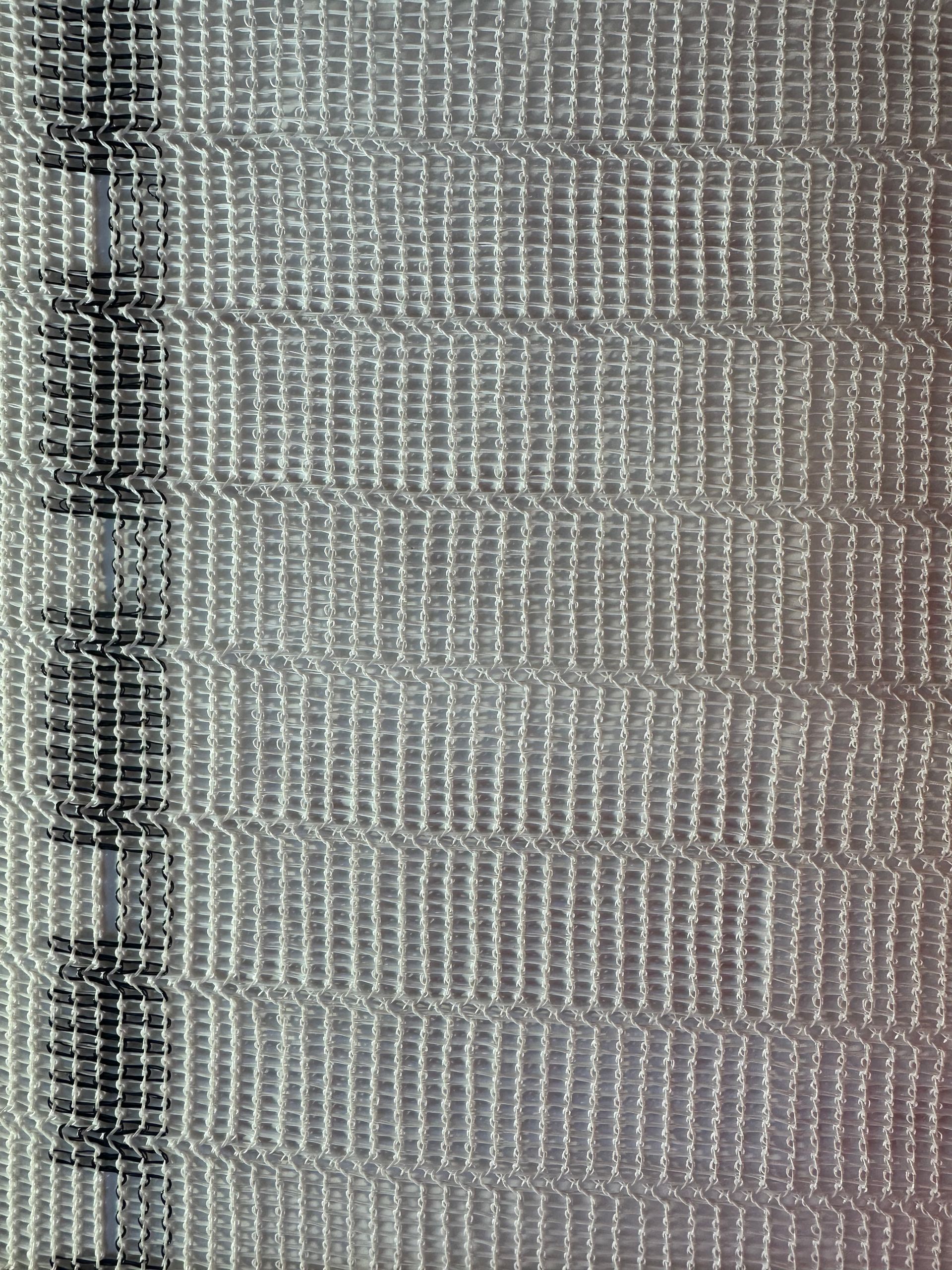 Close-up of a gray woven fabric with a dark vertical seam on the left edge