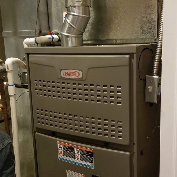A man is working on an air conditioner while taking notes.